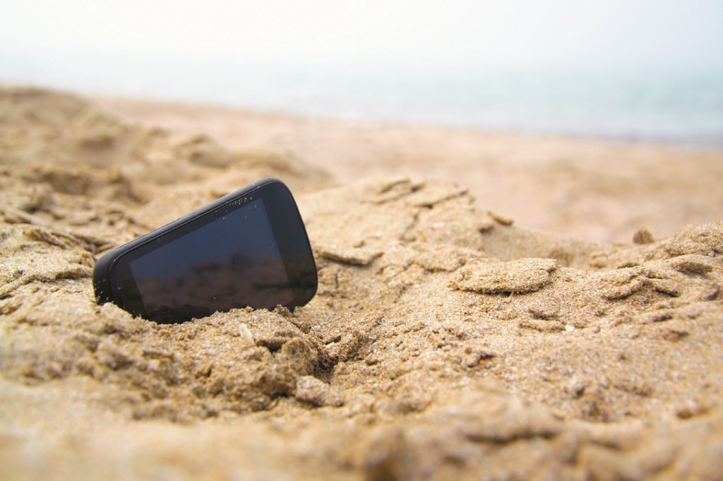 Mobile touch phone in sand on a beach